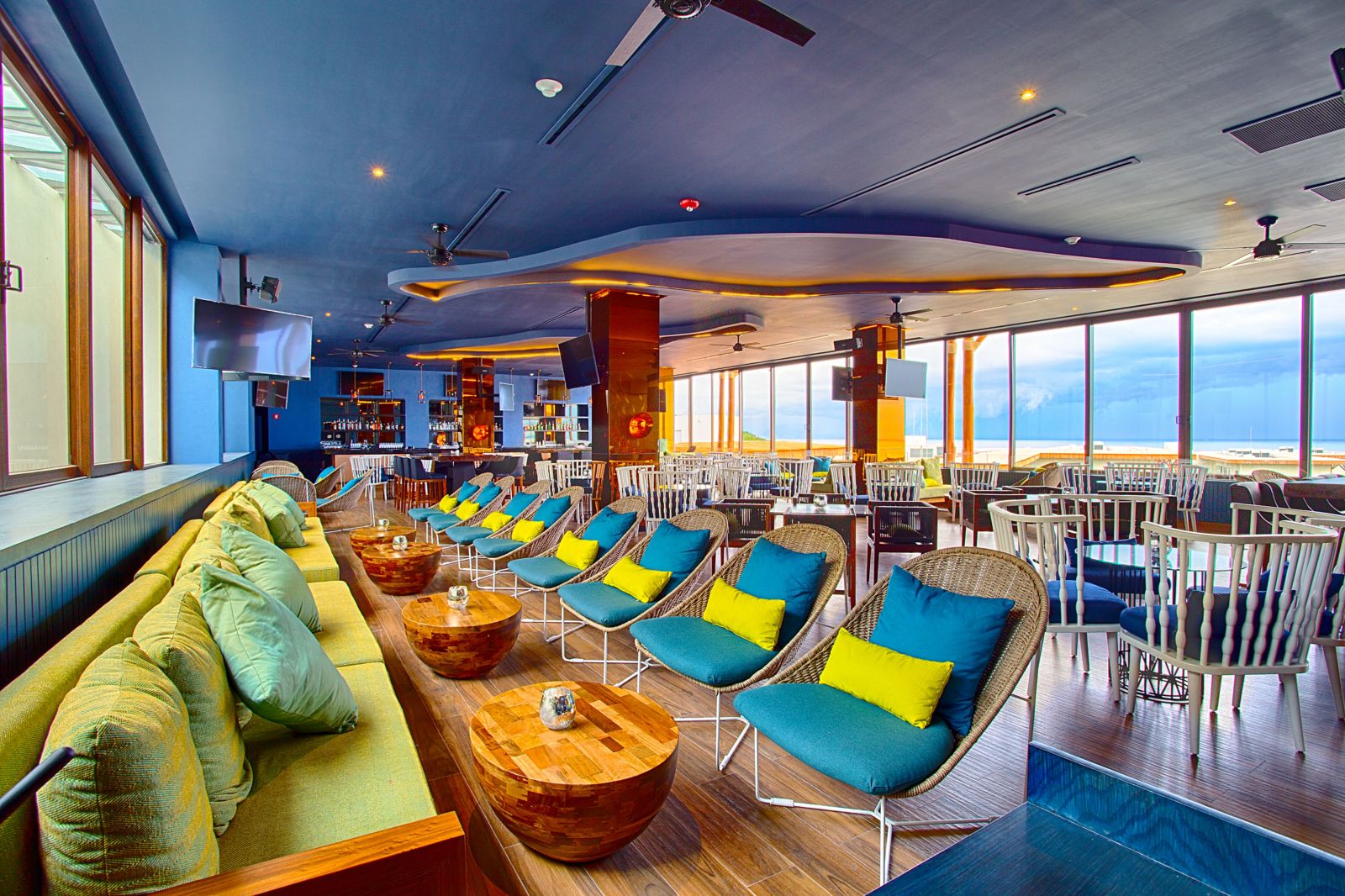 Vibrant lounge bar with colorful seating, ocean views, and a relaxed tropical atmosphere