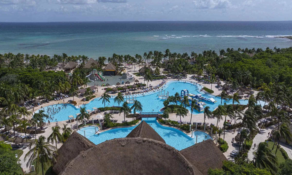 Main swimming pool at Grand Palladium Colonial surrounded by tropical gardens and palm trees