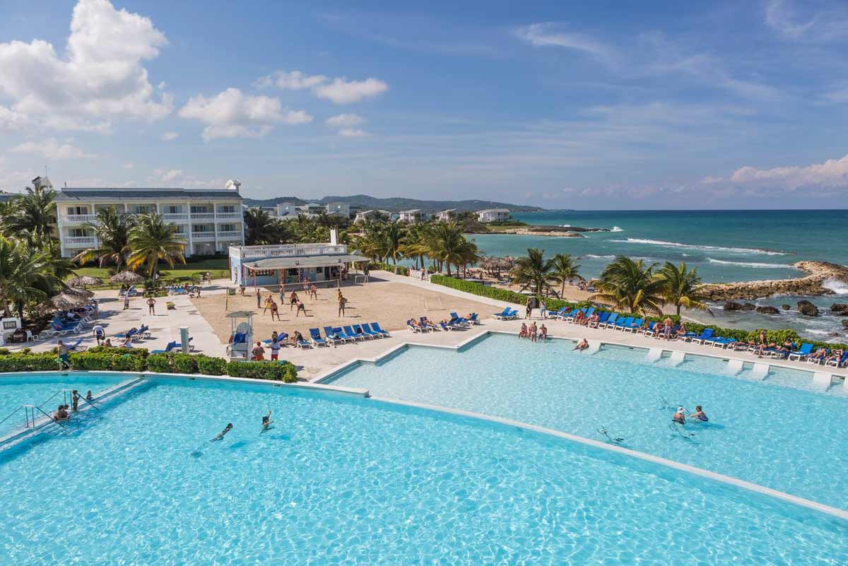 Sunset Cove beach at Grand Palladium Lady Hamilton with white sand, calm Caribbean waters, and complimentary loungers and umbrellas