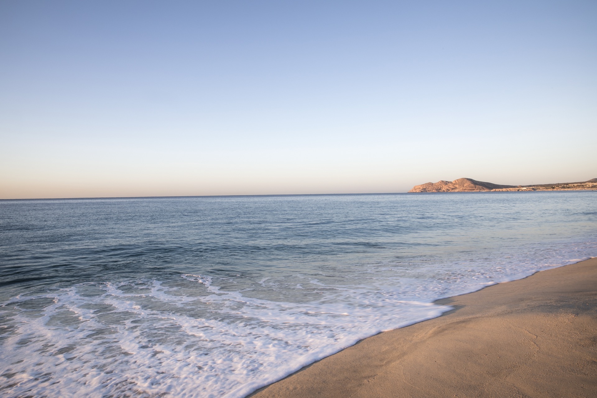 Golden sandy beach at sunset with Sea of Cortez and mountain silhouette