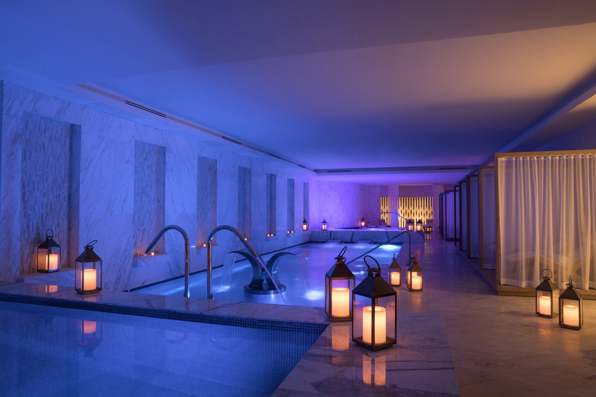 Spa hydrotherapy circuit with blue ambient lighting, lanterns, and plunge pools