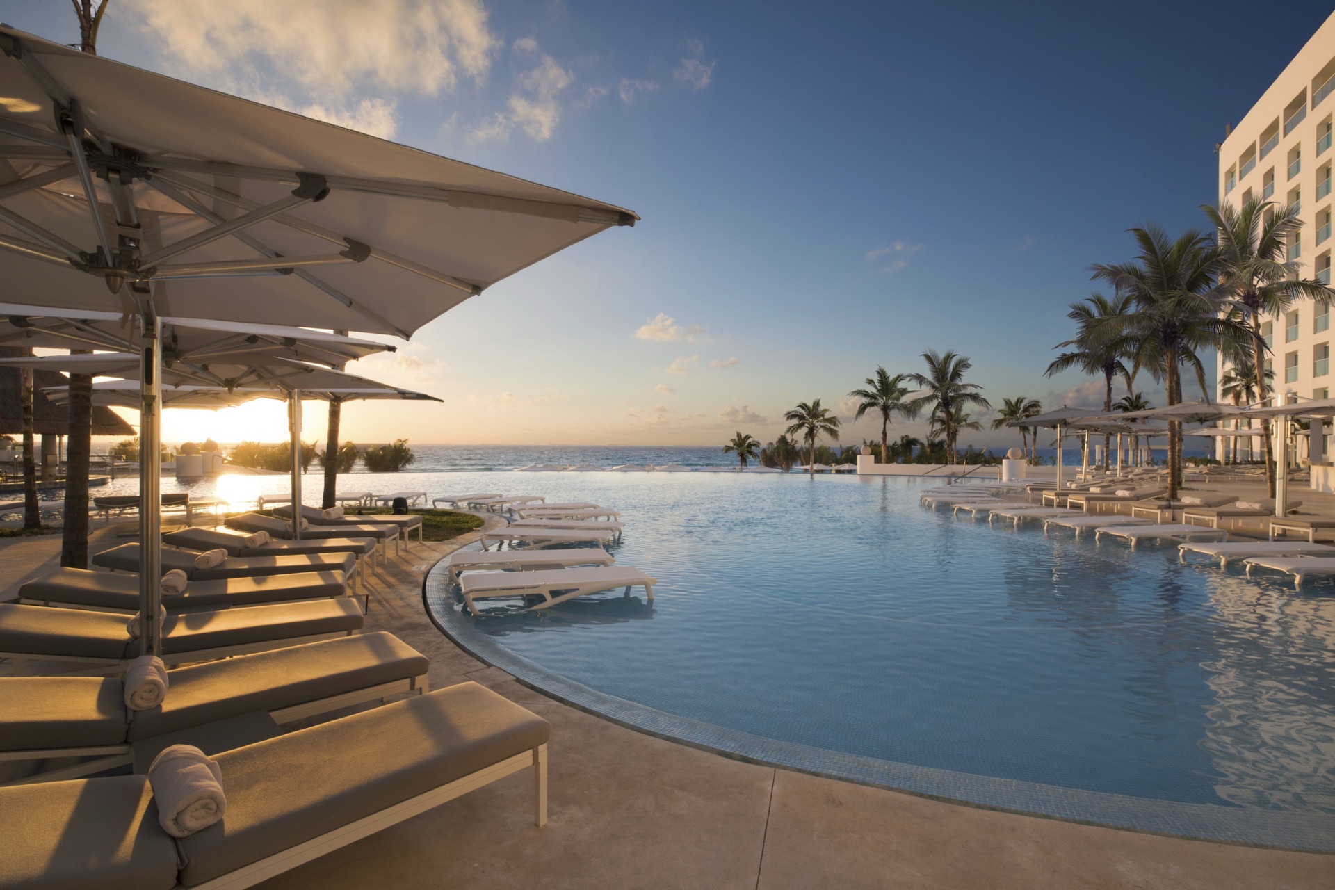 Main infinity pool at sunset with resort building and ocean views