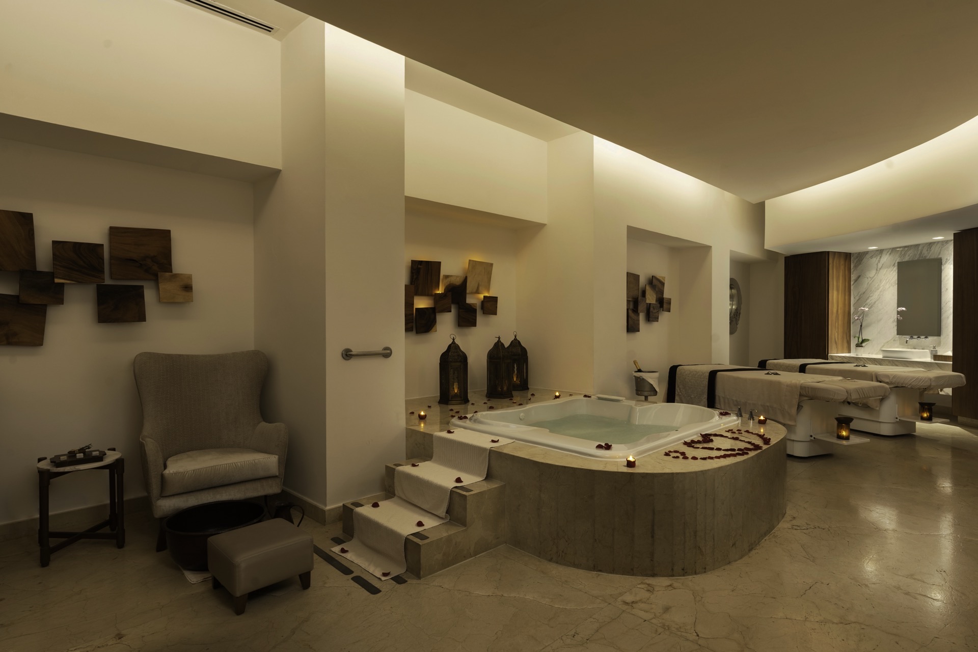 Couples spa suite with hydrotherapy tub, massage beds, and rose petals