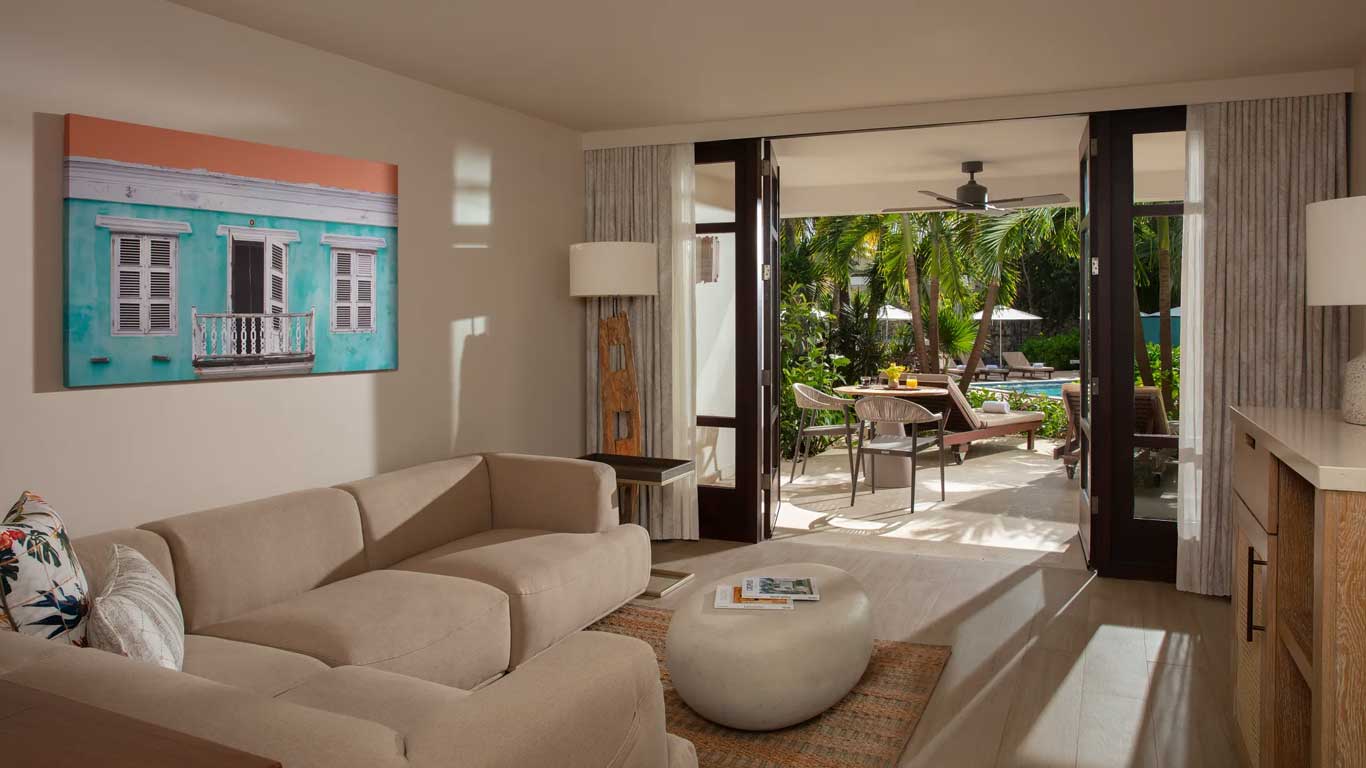 Master Suite living area with sectional sofa, Curacaoan colonial artwork, and pool-view terrace