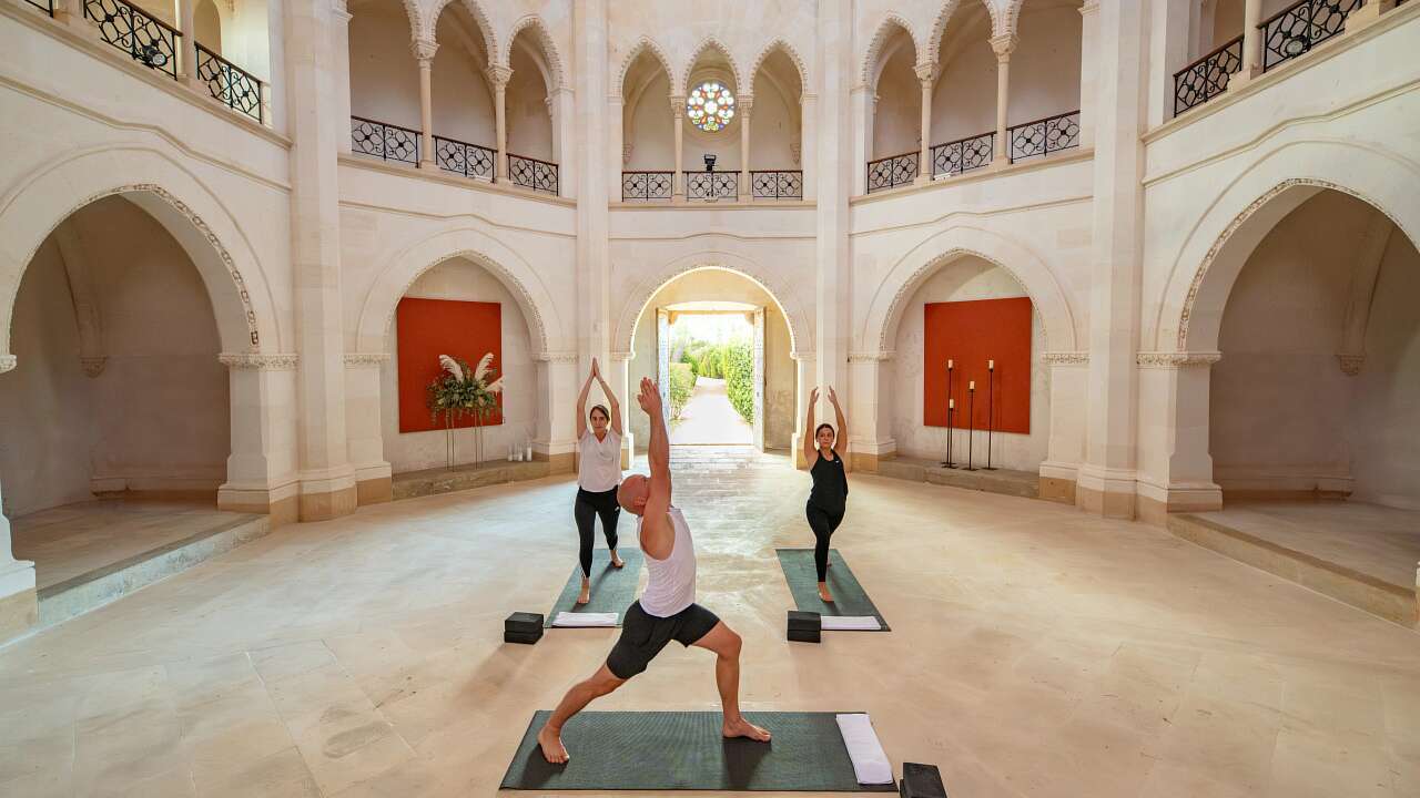 Yoga session inside the restored neo-Gothic chapel with soaring arched ceilings, rose window, and gallery balconies