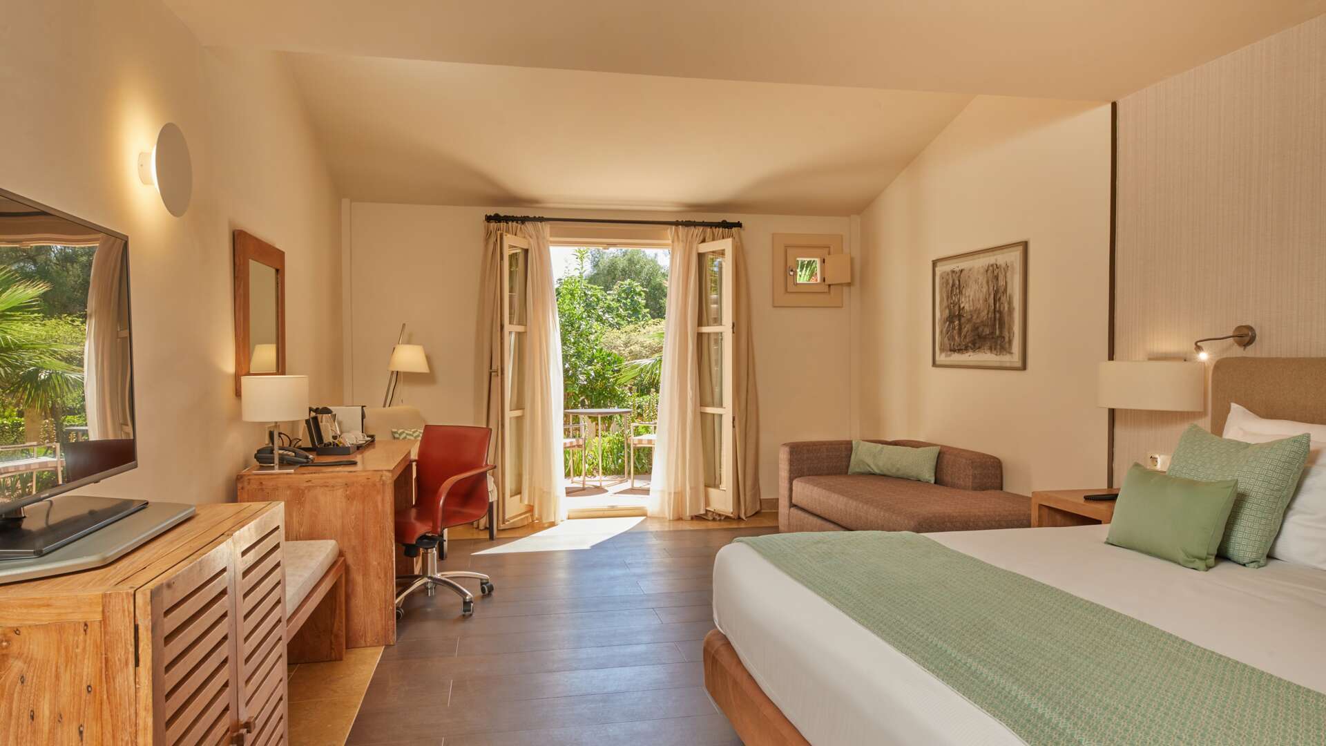 Double Deluxe Ponent Room with king bed, wooden desk, sofa nook, and balcony overlooking lush garden