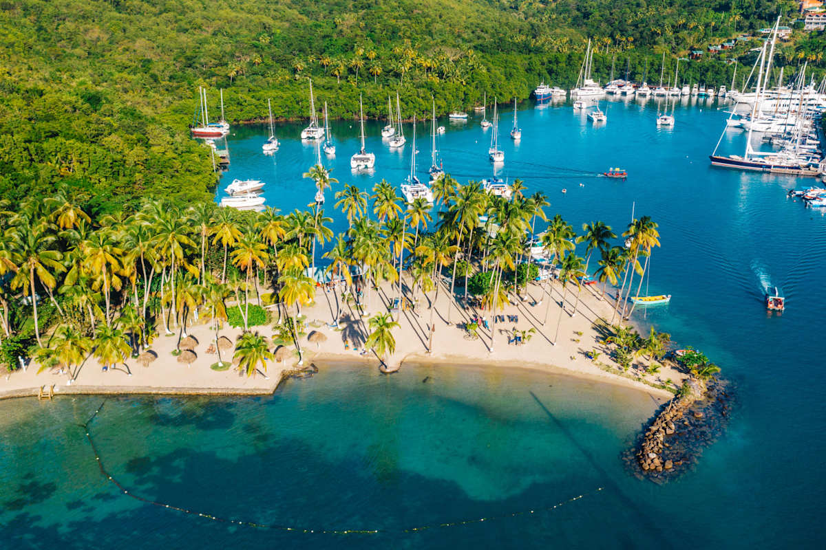 Aerial view of Marigot Bay showing the resort, marina, and volcanic white-sand beach framed by verdant hillsides