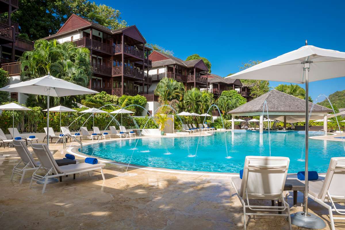 Infinity pool overlooking Marigot Bay harbour with sun loungers and tropical palm trees