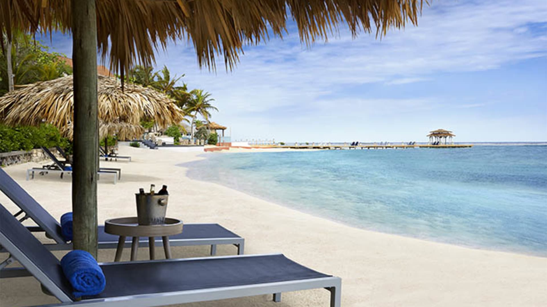 Private beach at Zoetry Montego Bay with palapa umbrellas and pier